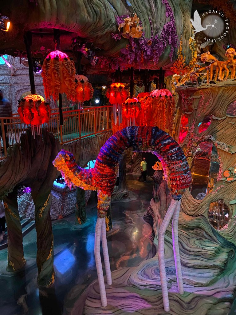 In the foreground is a skinny quadruped. Above are dangling fancy round lights. In the background are  a lot of other things that I really can't describe.